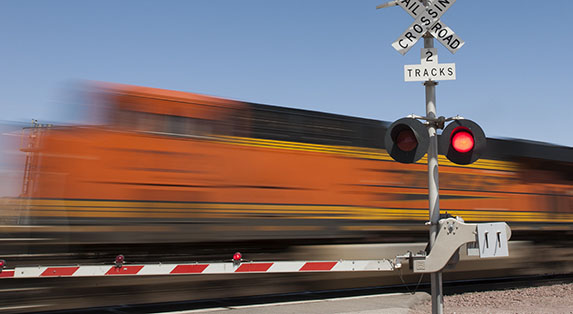 A BNSF train travels at high speed through a grade crossing.